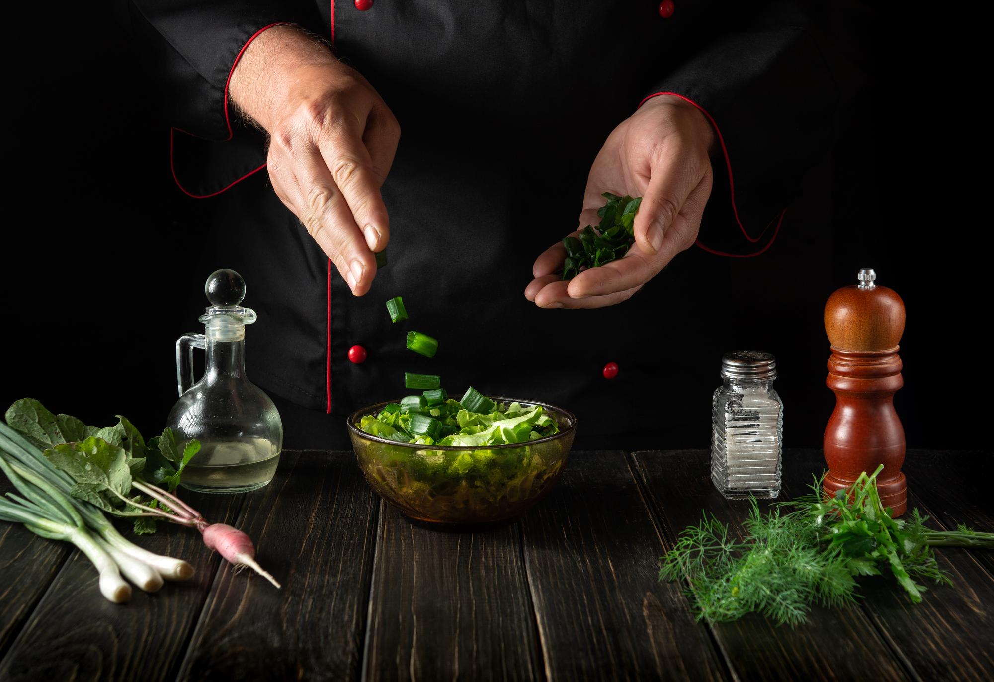 Chef arranging herbs on a wooden board in warm light